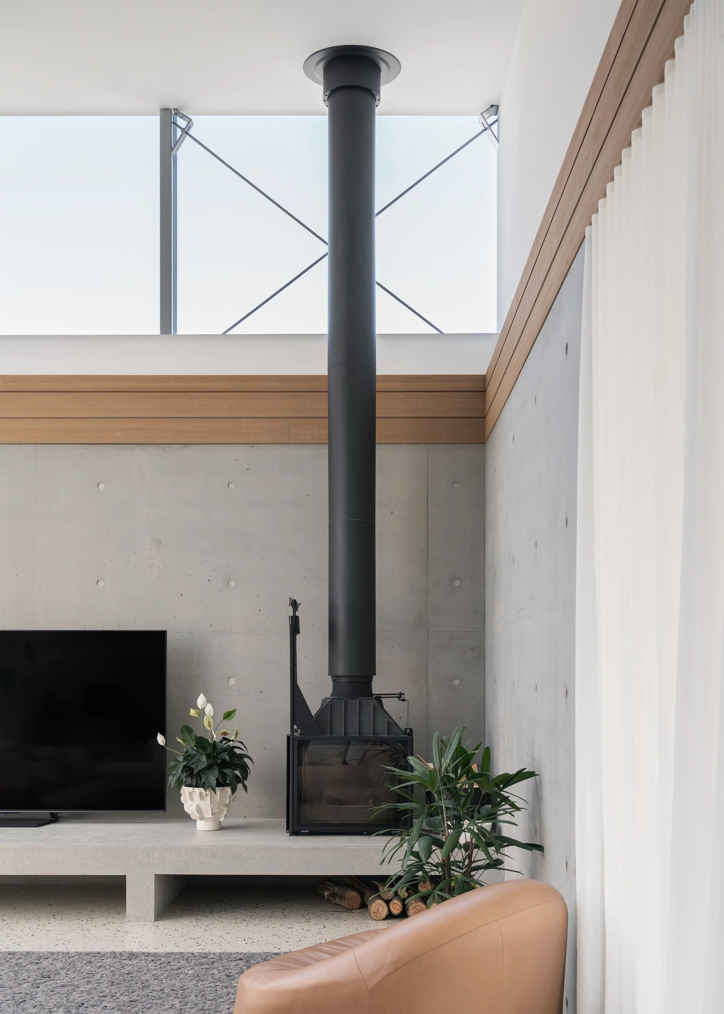 Concrete hearth with Cheminees Philippe fireplace and clerestory glazing bringing high-level natural light into the main living room at Channel in Mornington, Victoria, Australia.
