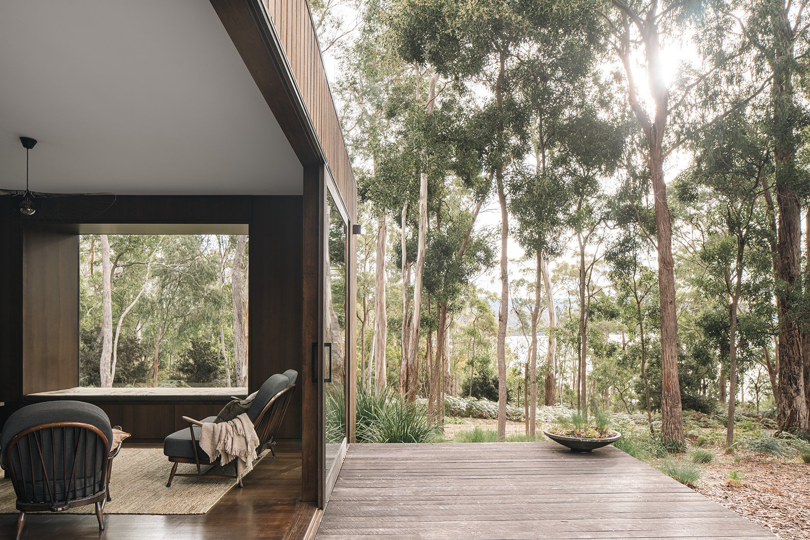 Living area at Killora Bay opening onto a timber deck, creating a continuous threshold between the interior and surrounding bushland.