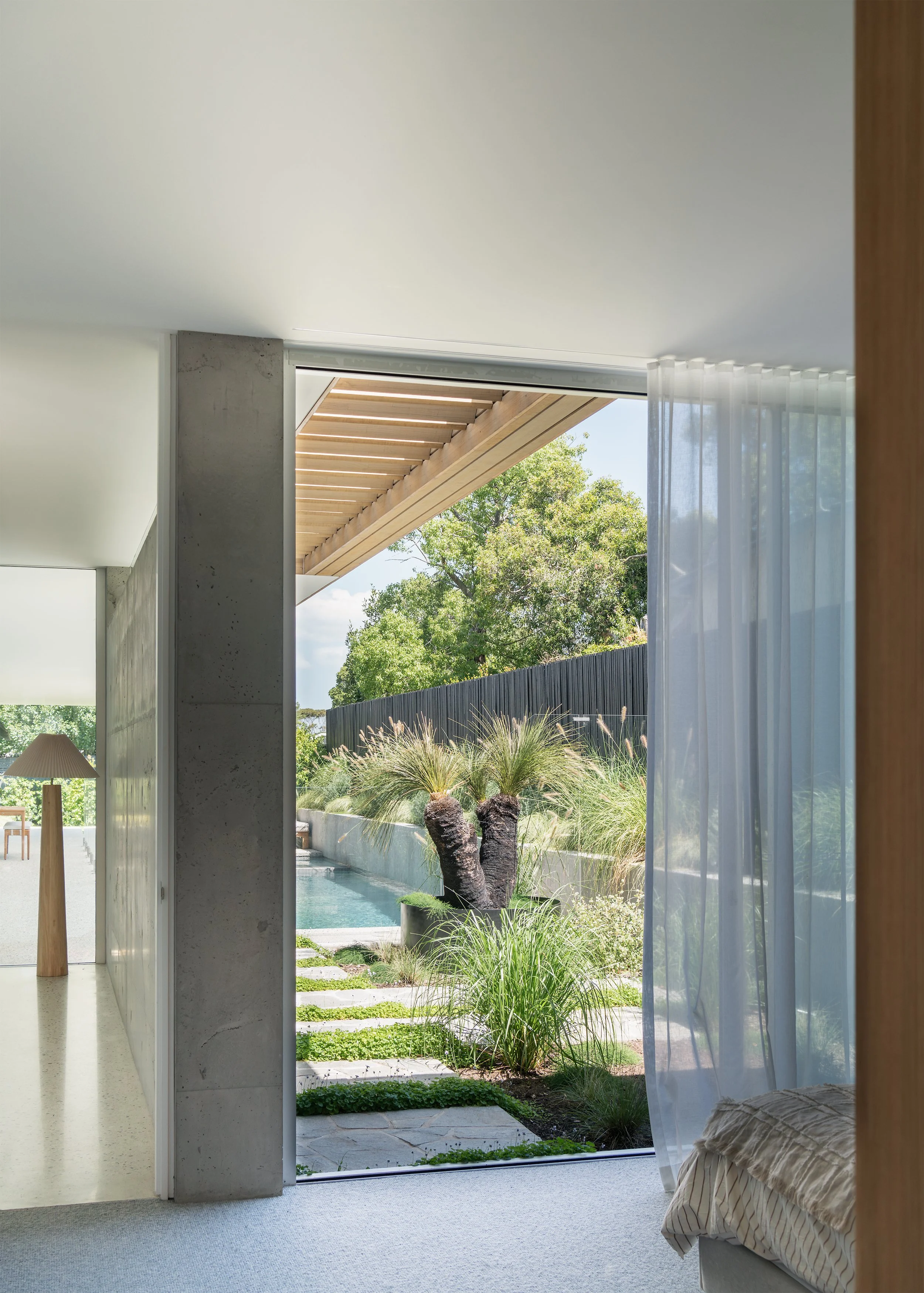 Bedroom opening directly to the landscaped garden and swimming pool beneath the timber pergola at Channel in Mornington.