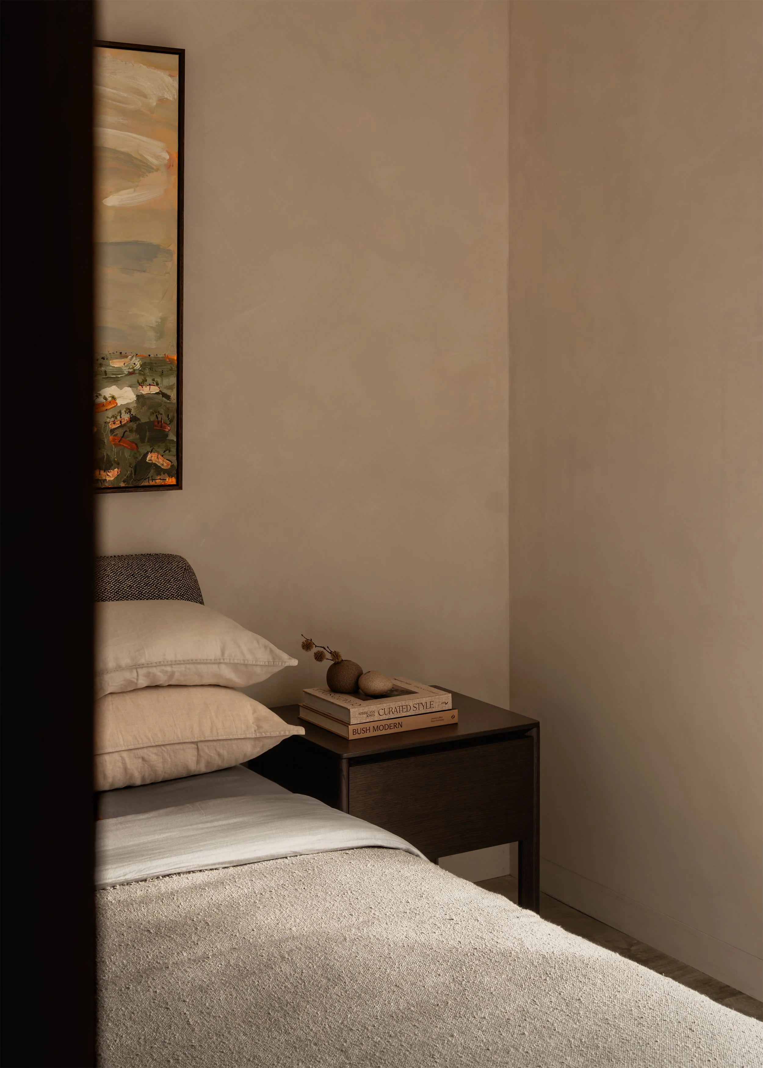 Bedroom at Matchbox with soft neutral finishes, Cosh Living bedside table and framed artwork against a textured paint wall.