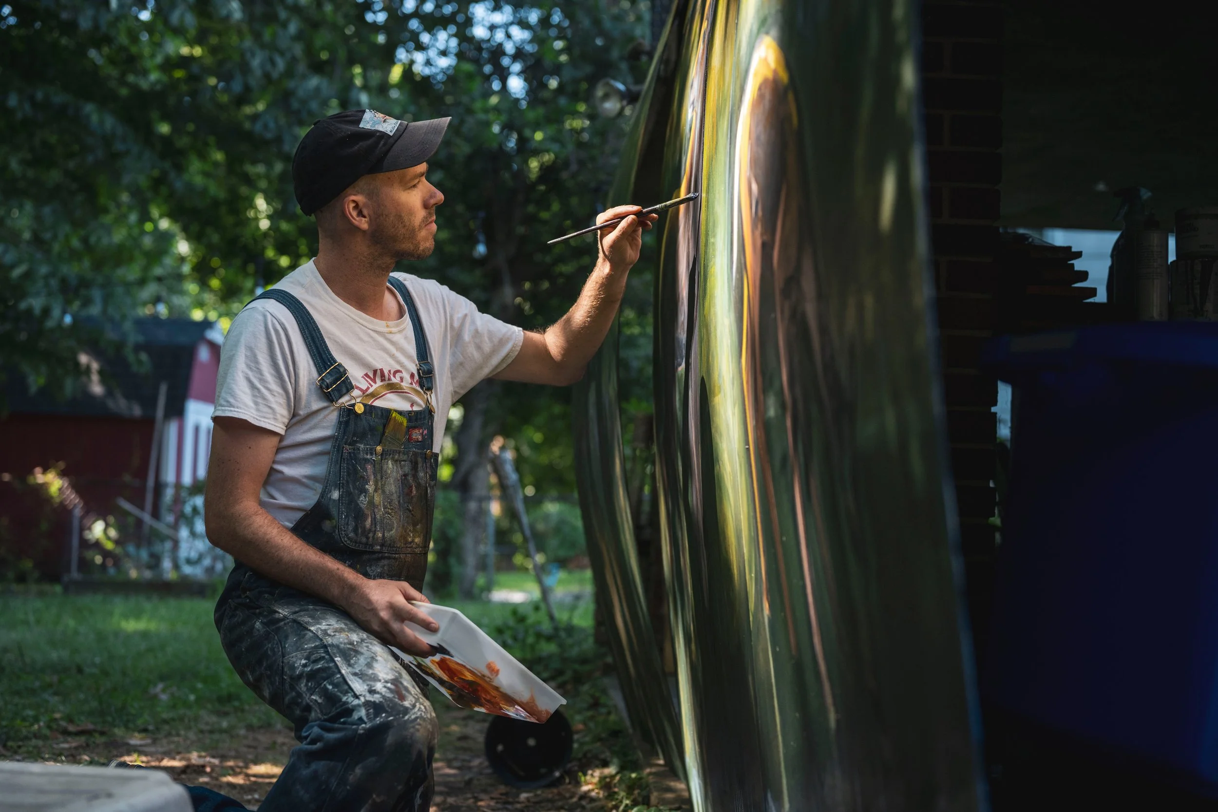 This picture depicts artist Collin Cessna kneeling painting a picture to demonstrate his Etsy shop