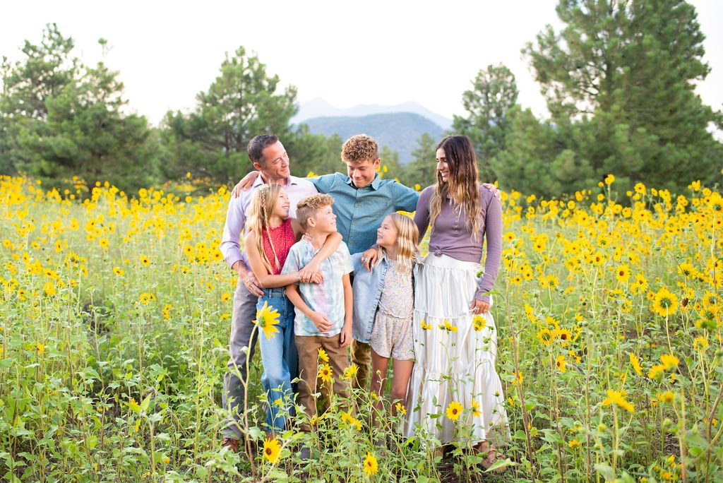 Family embracing and smiling at eachother in the wildflowers during Flagstaff family photography session