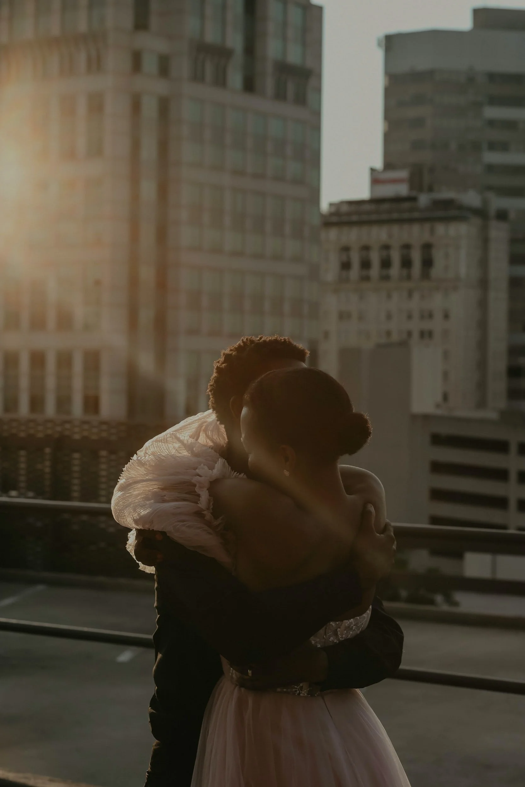 Couple embracing on rooftop with city skyline at sunset