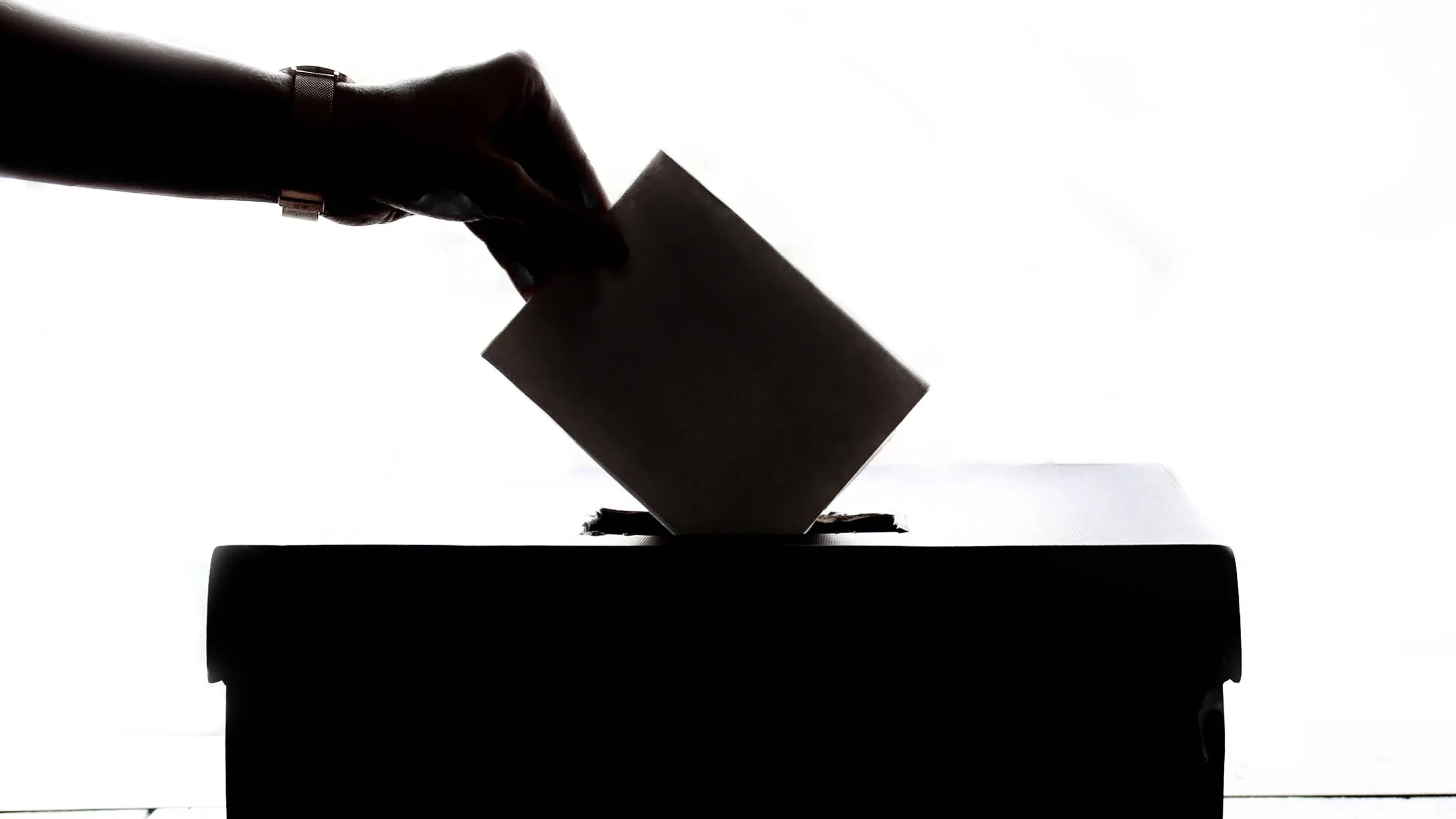 A hand casting a vote into a box