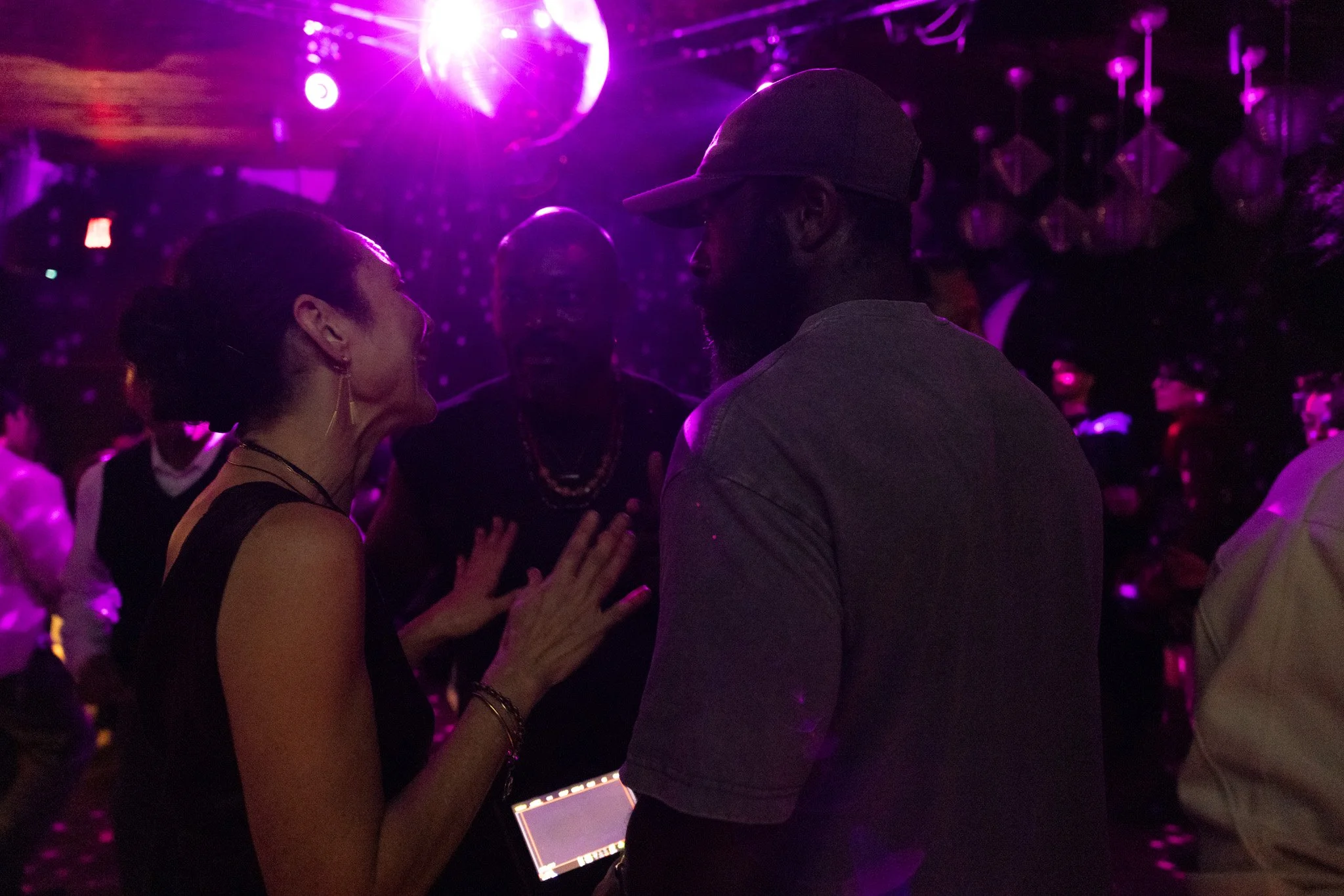 Lola Glaudini and Jimmy Jean-Louis in "Tu Viens D'où" dancing closely at a club with pink and purple lighting.