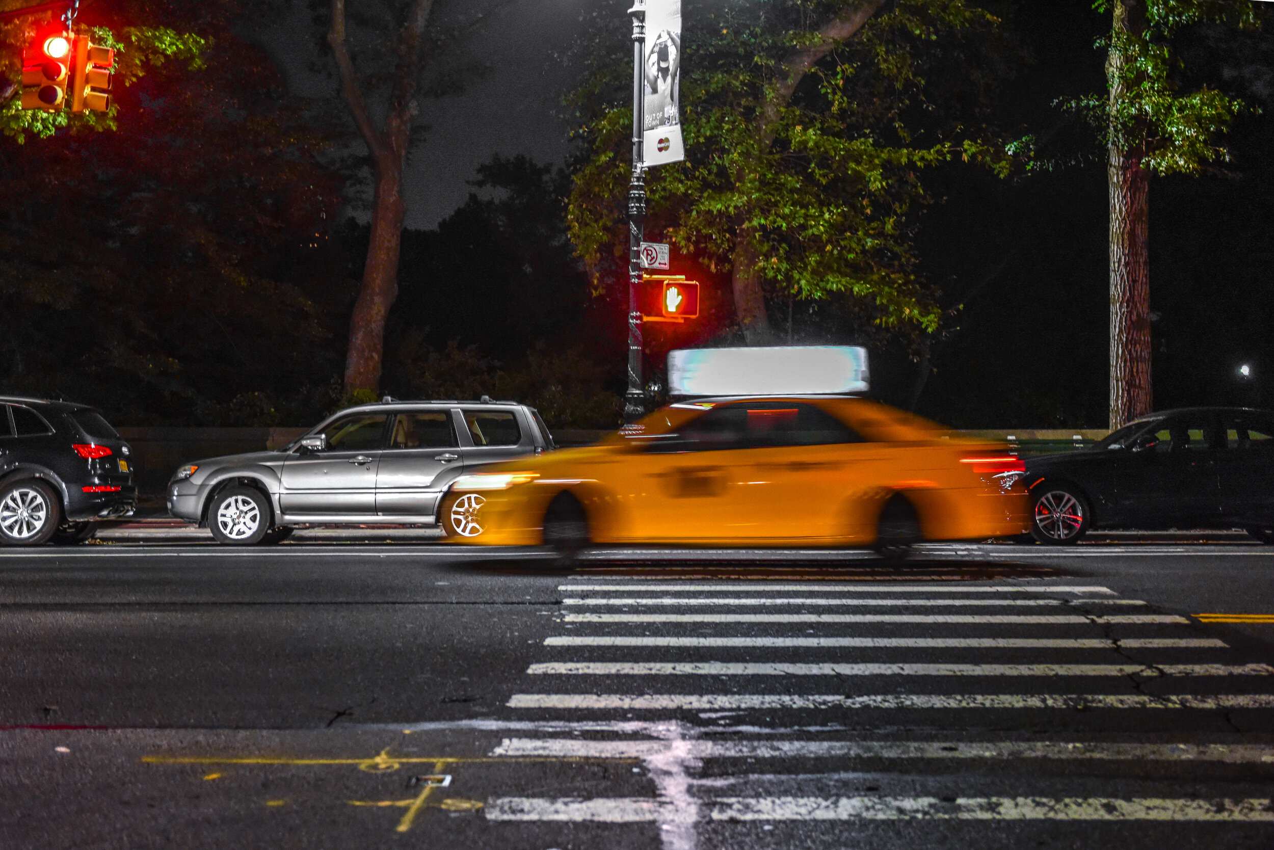 New York yellow cab speeding past Central Park West.