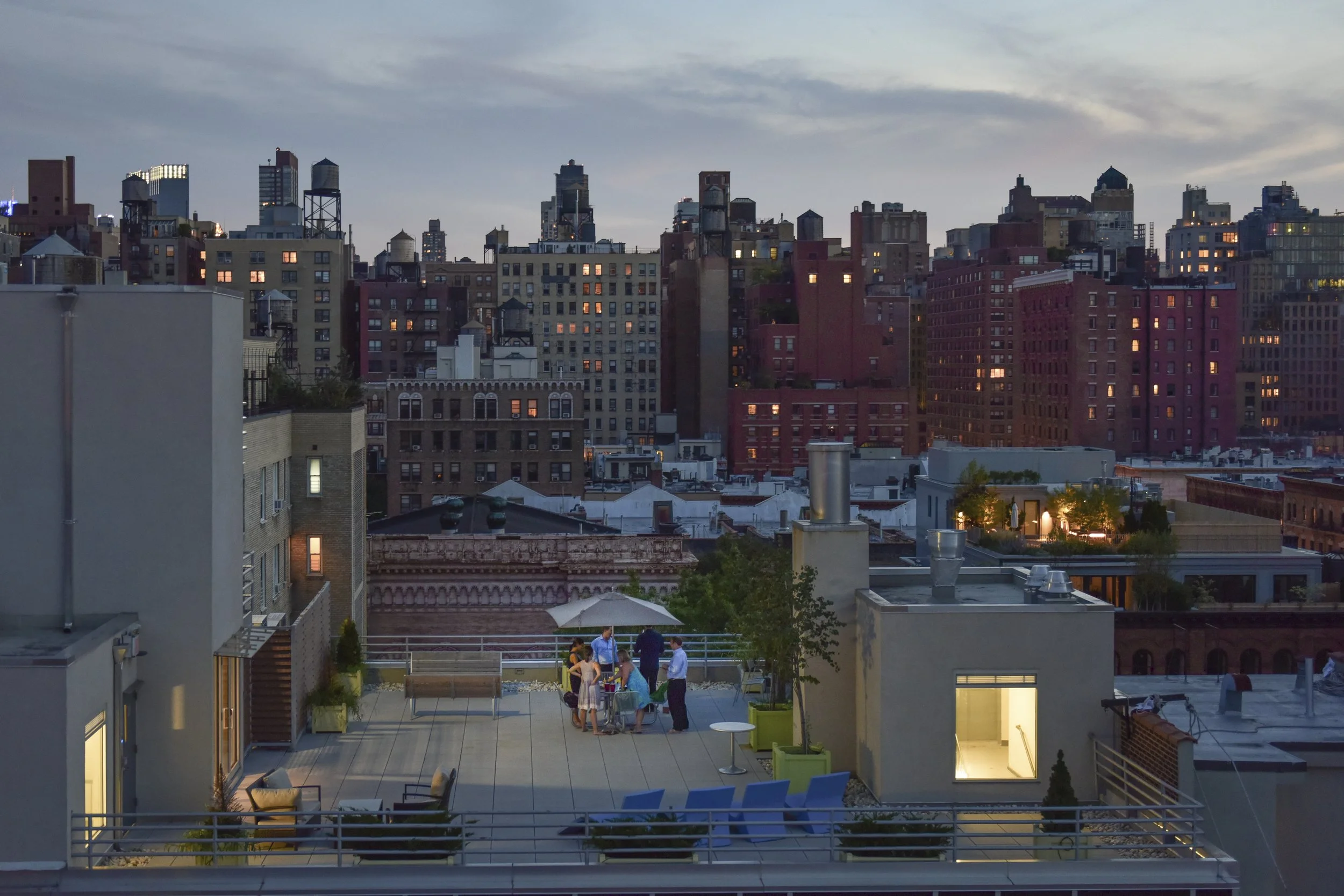 People are pictured relaxing on rooftops of Manhattan in summer of 2016. as the sun sets