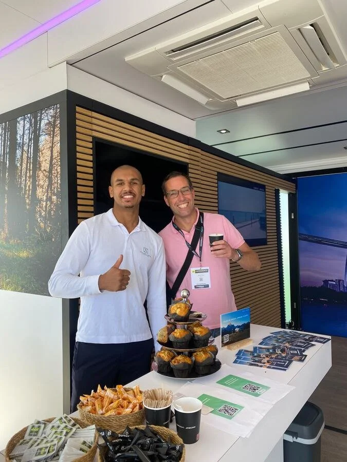 Tevreden bezoeker met koffie en muffins op de stand