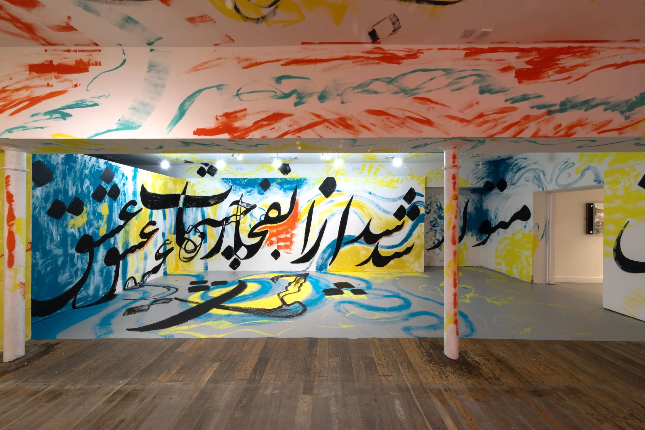 Panoramic view of the Elysium Gallery interior, with layers of red, blue, yellow, and black Persian calligraphy painted across the walls and ceiling.jpeg