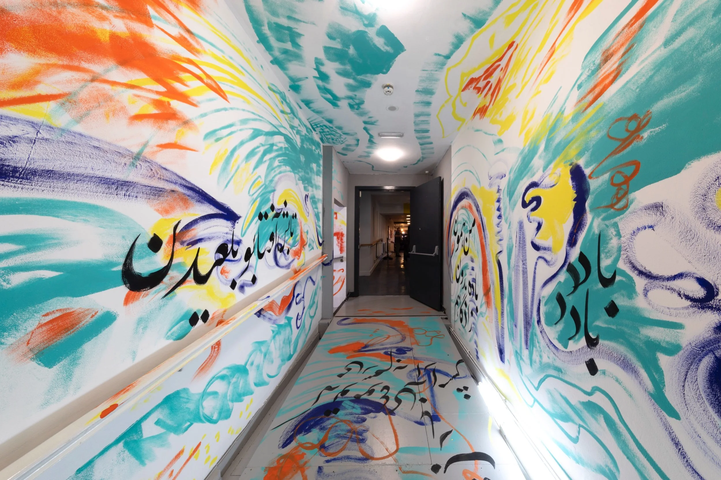 View along a corridor within the gallery where Persian calligraphy in red, blue, and yellow flows across the walls and ceiling.jpeg