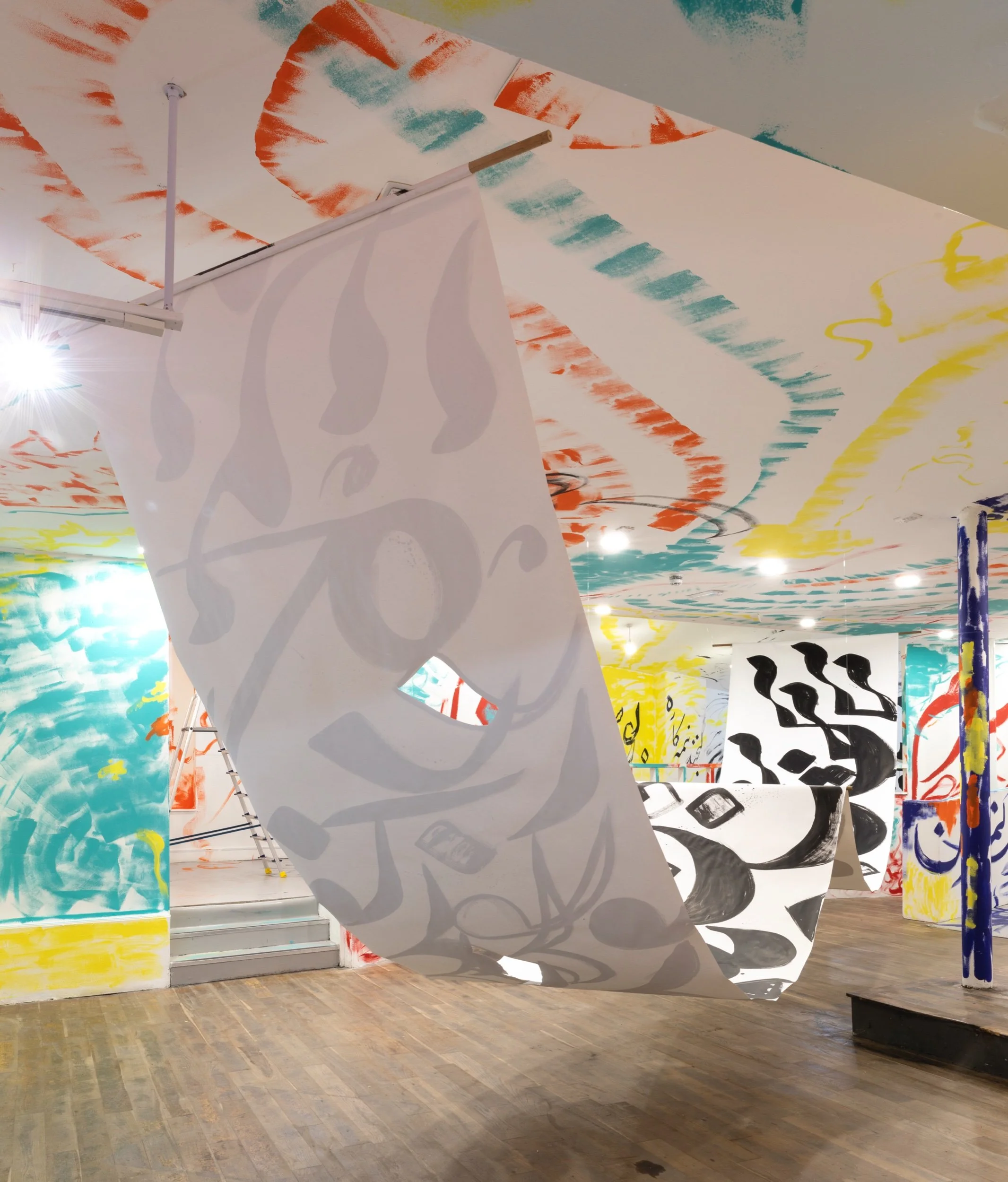 Wide shot from behind a large hanging scroll painted with black Persian calligraphy.jpeg