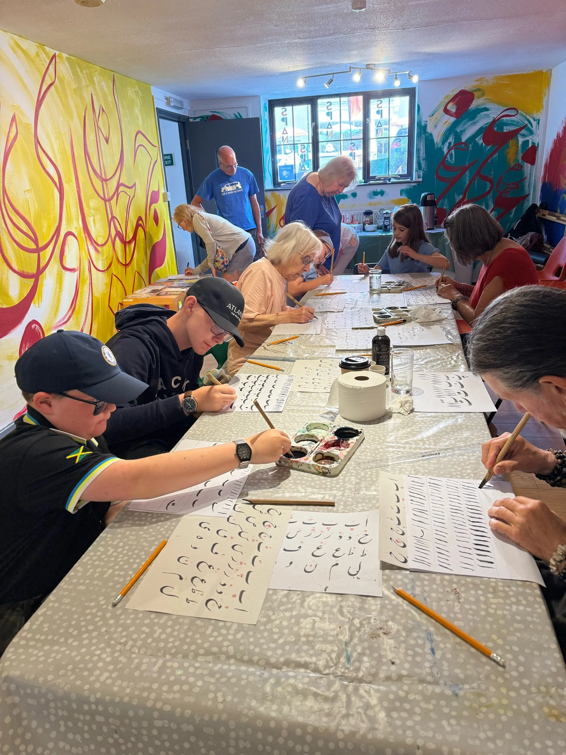 Participants sit at a long table to enjoy creating Persian calligraphy in the gallery.jpeg