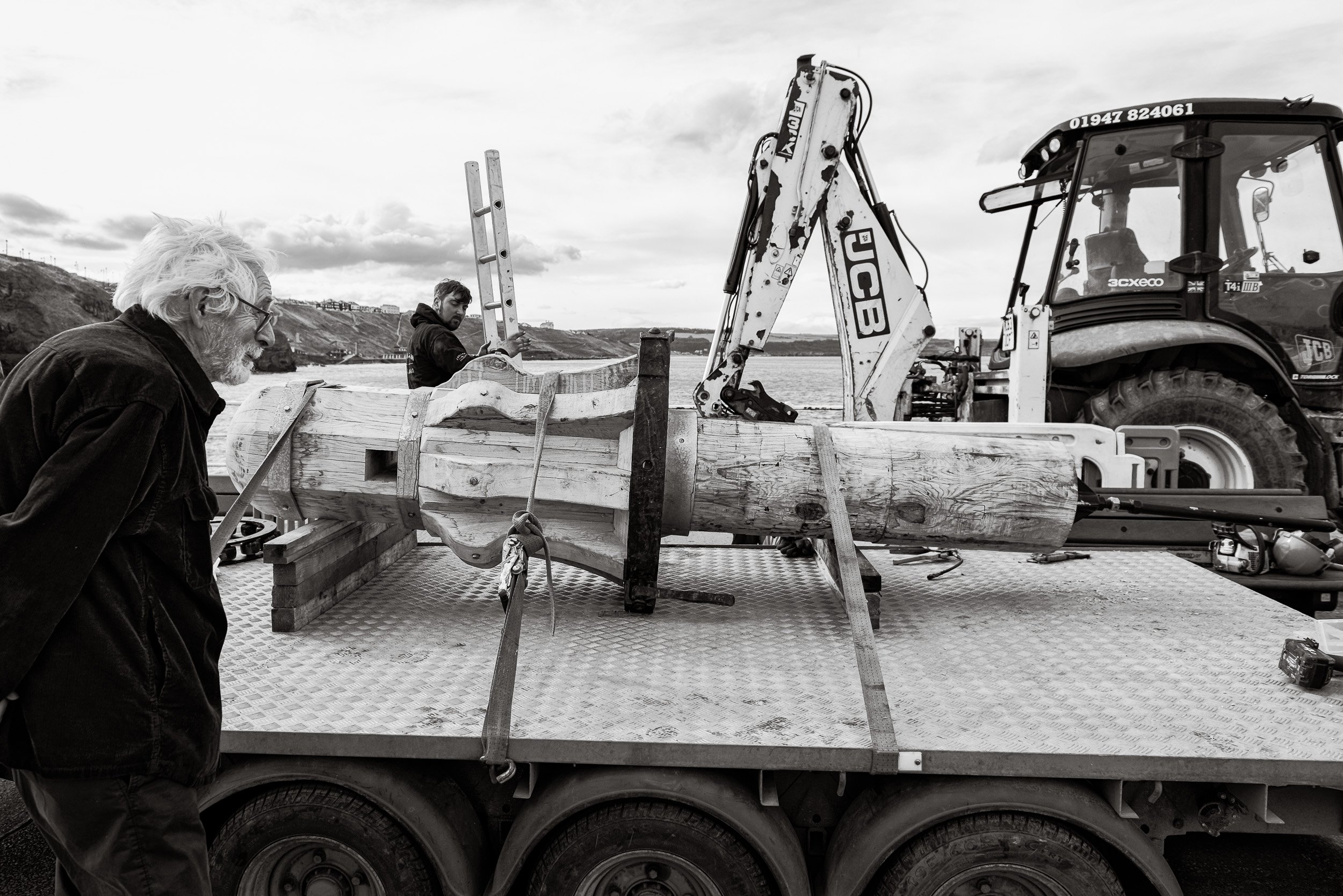 An onlooker looks with curiosity at a handcrafted timber capstan lying on a trailer awaiting installation as part of the heritage project to replace the capstans on Whitby Harbour.