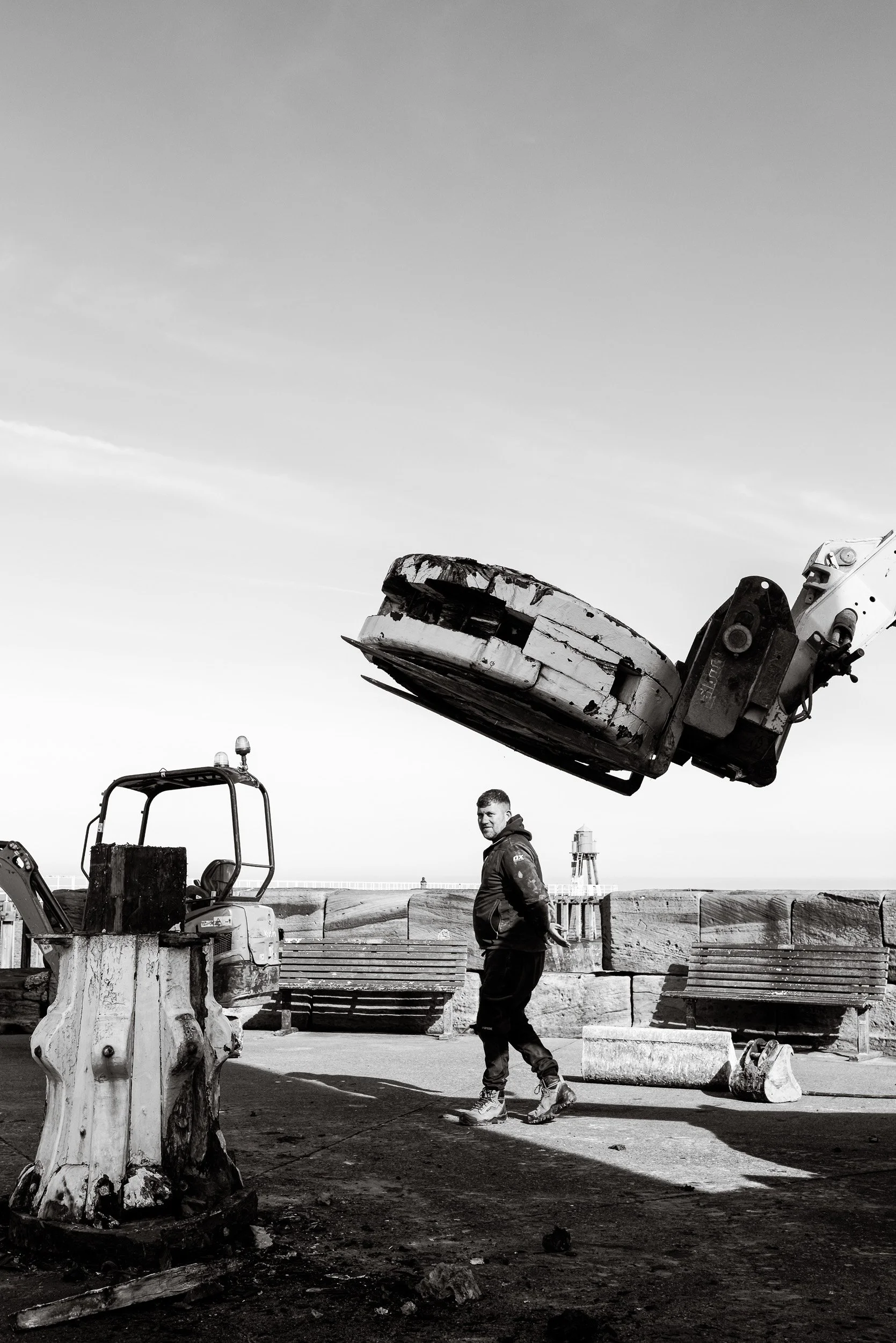A worker watches in the background as the top of a weathered timber capstan is removed as part of the heritage capstan replacement project on Whitby Harbour.