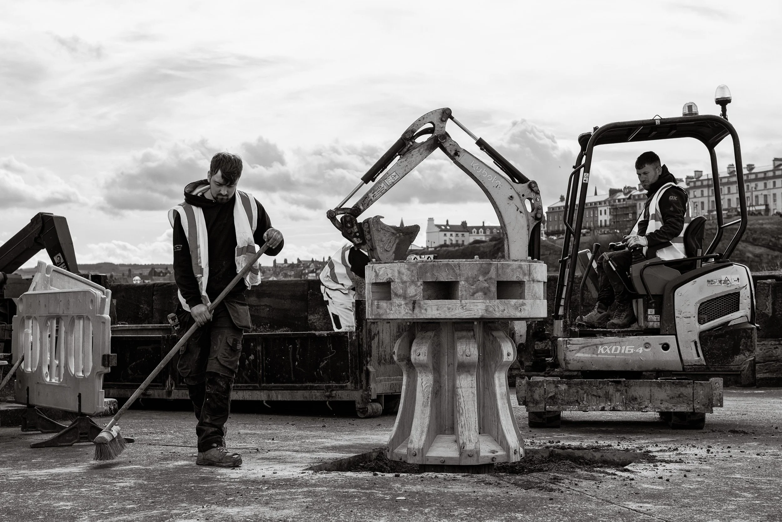A joiner from J Hallam Joinery carefully cleans the ground following the installation of a handcrafted timber capstan as part of the heritage project to replace the capstans on Whitby Harbour.
