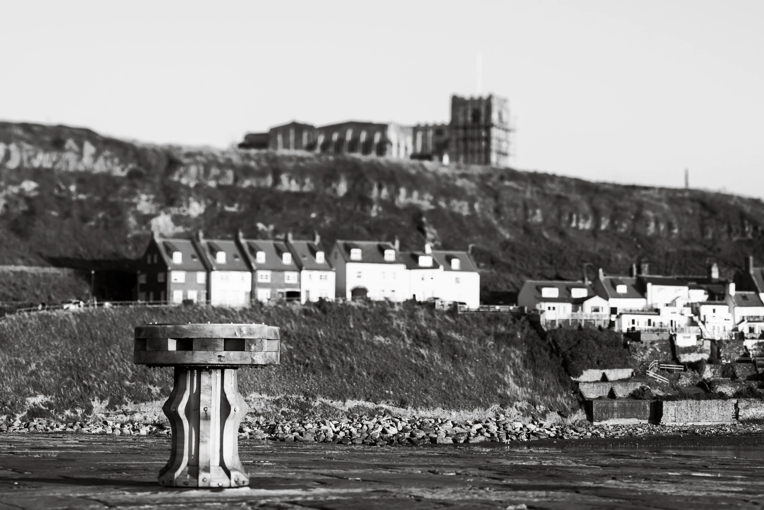 A completed handcrafted timber capstan sits on the pier with Whitby Abbey in the background as part of the heritage project to replace the capstans on Whitby Harbour.