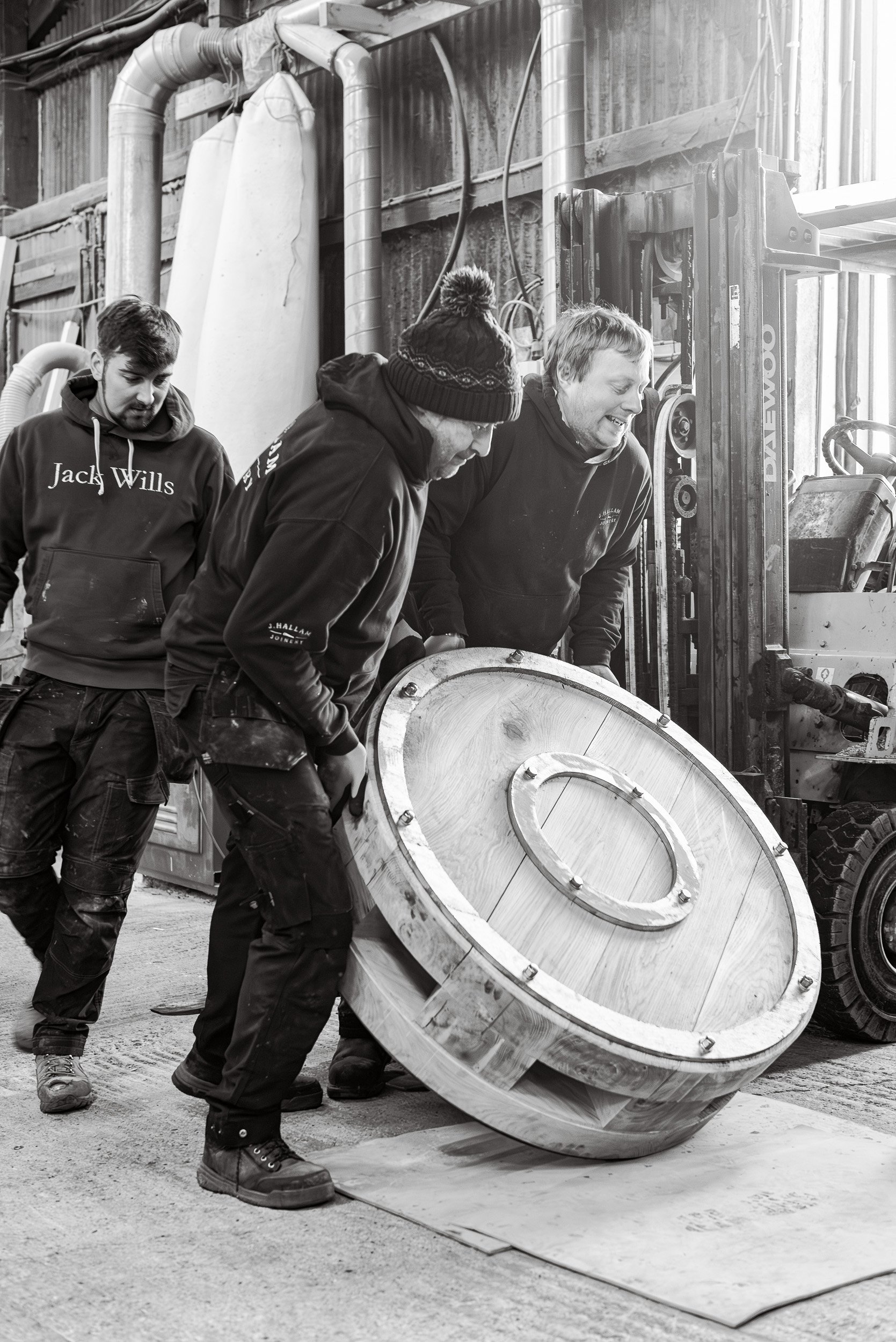 Workers from J Hallam Joinery strain to lift a heavy timber component of a replacement capstan for Whitby Harbour.