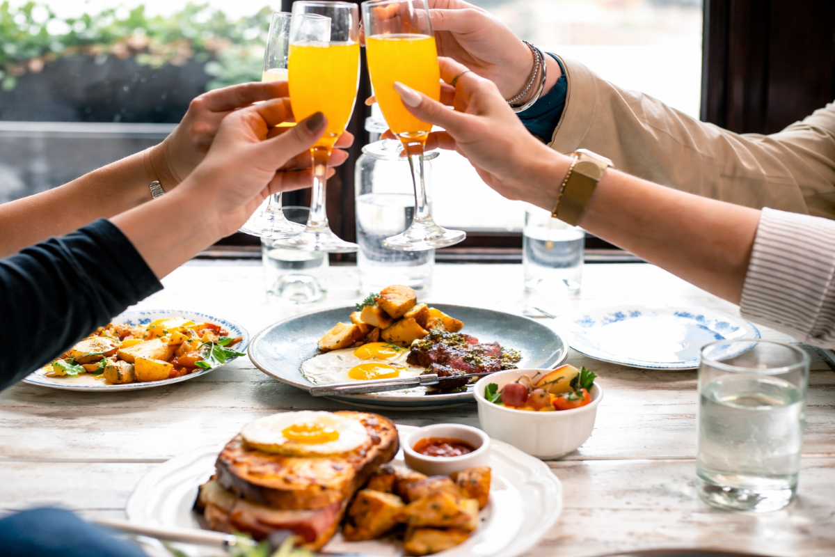 Brunch toast with mimosas and dishes.png