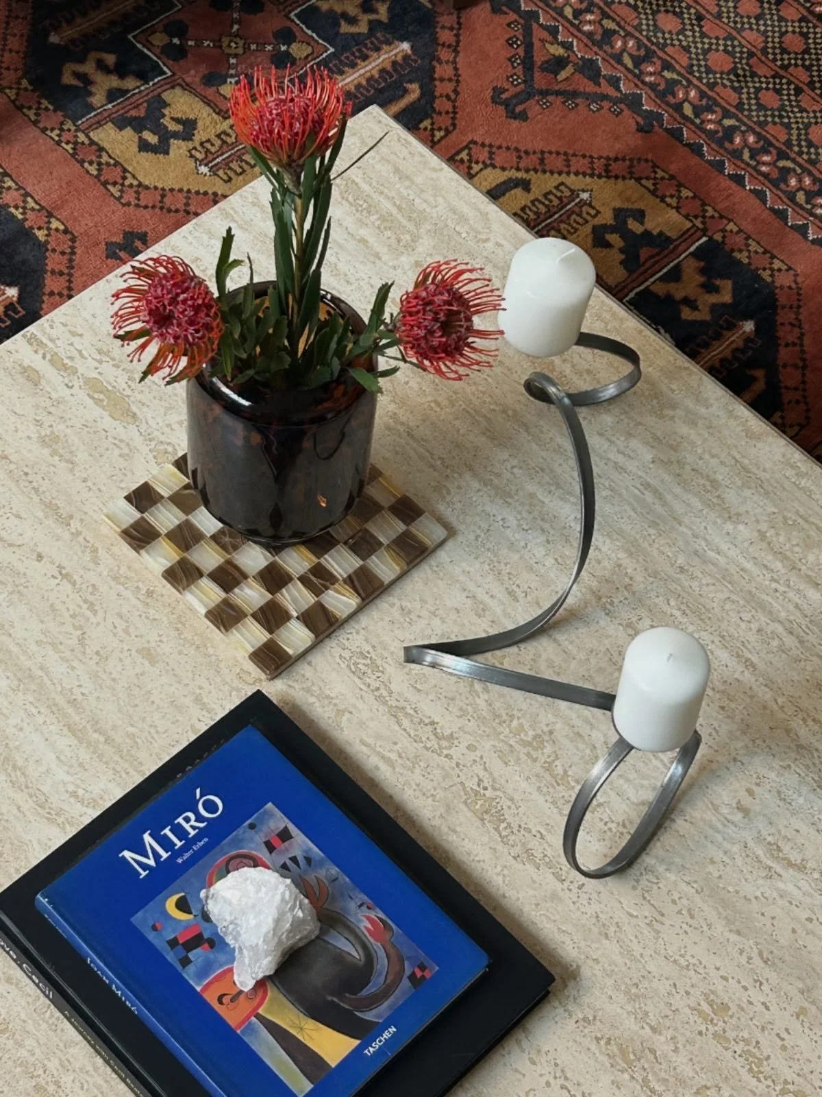 Coffee tables are one of our favorite things to style. Here, we used the chessboard as a bold yet small-scale pattern that plays nicely with the area rug, and paired it with the blue Mir&oacute; book for contrast. We love incorporating metals too, wh