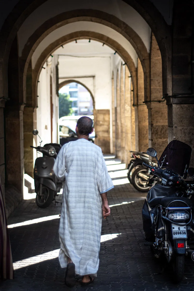 An older man walks along the arched corridors of the medina