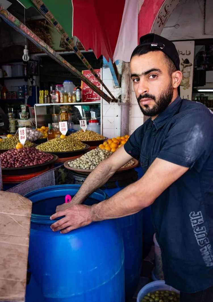 A young vendor scoops Castelvetrano olives from a barrel