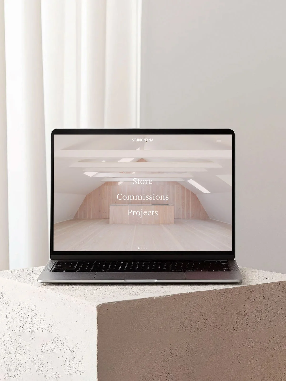 A stone plinth with a Macbook showing the Studiomama homepage.