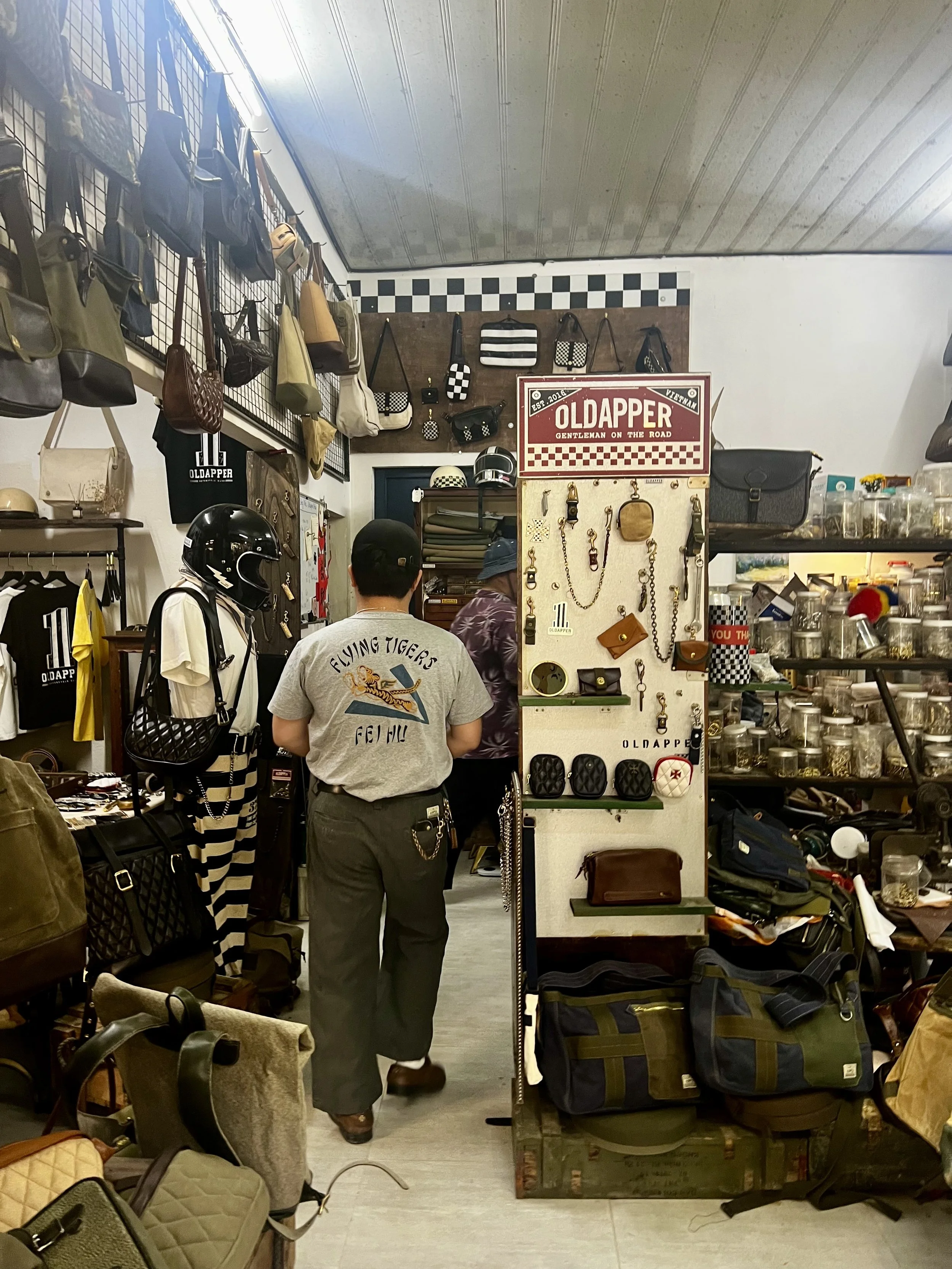 Inside a vintage-style store selling bags, accessories, and leather goods, with two customers browsing.
