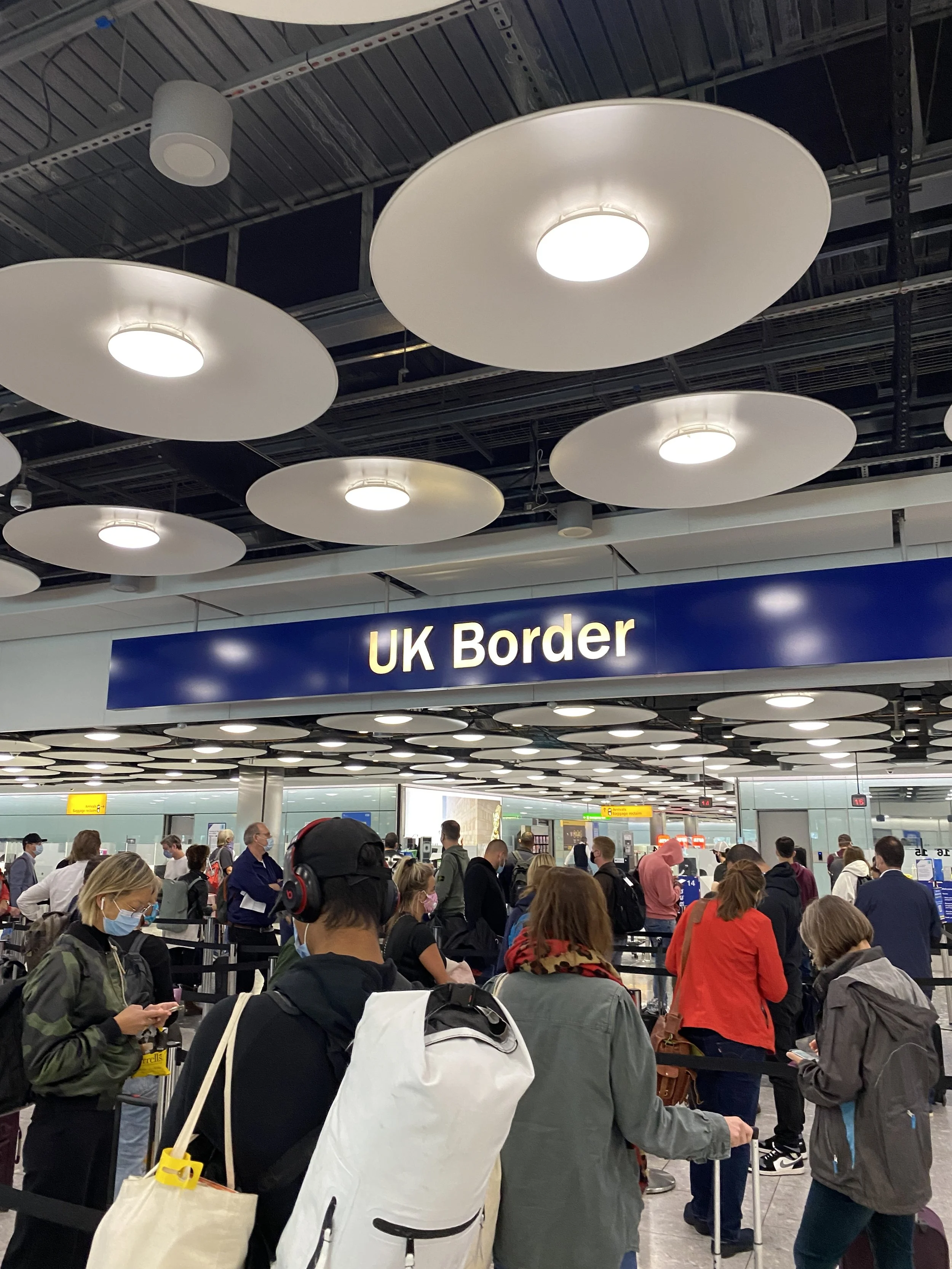 People waiting in line at the UK Border immigration checkpoint in an airport.