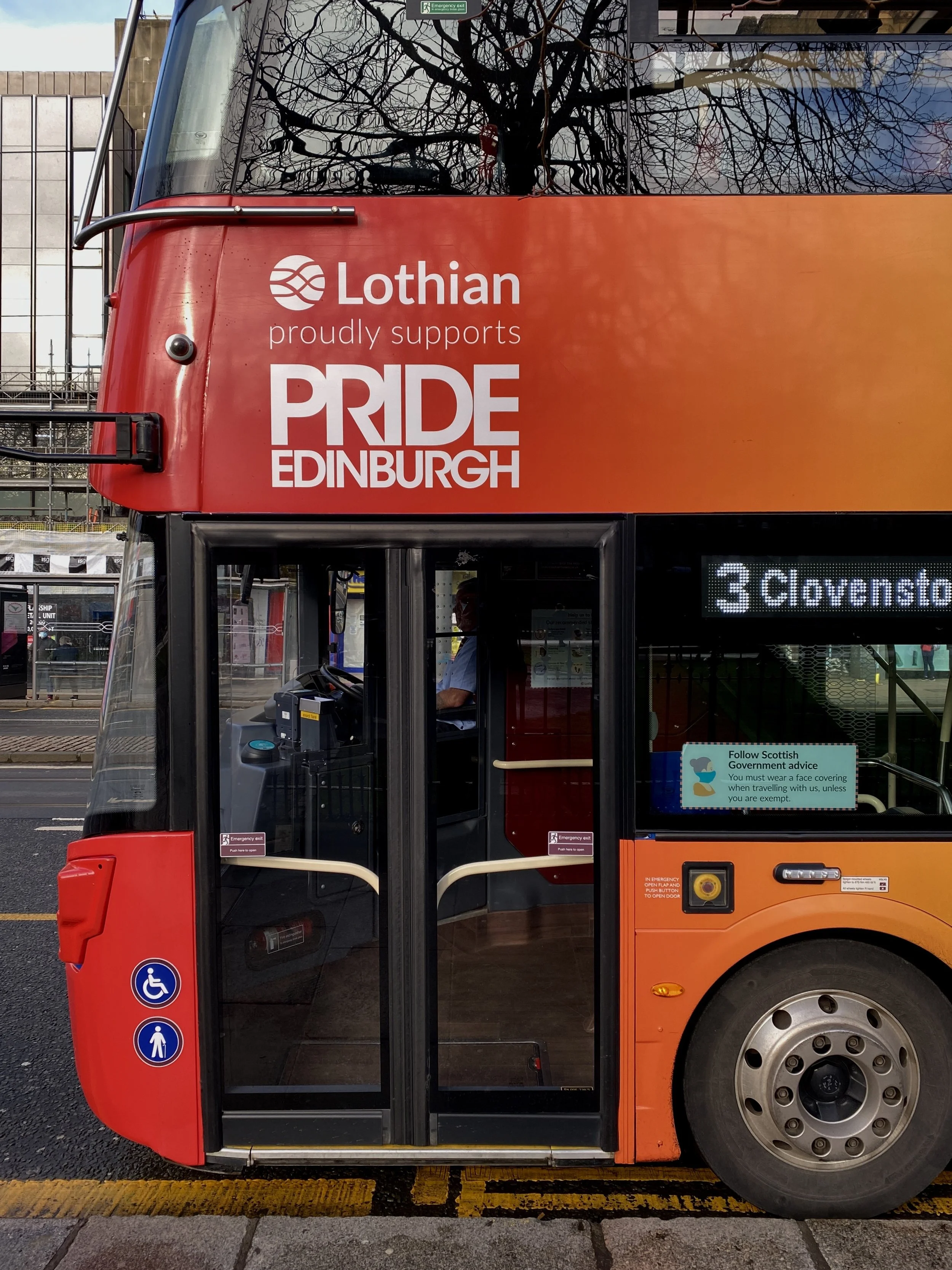 A red double-decker bus with advertising for Pride Edinburgh, supported by Lothian, with route number 3 to Corstorphine, parked on a city street.