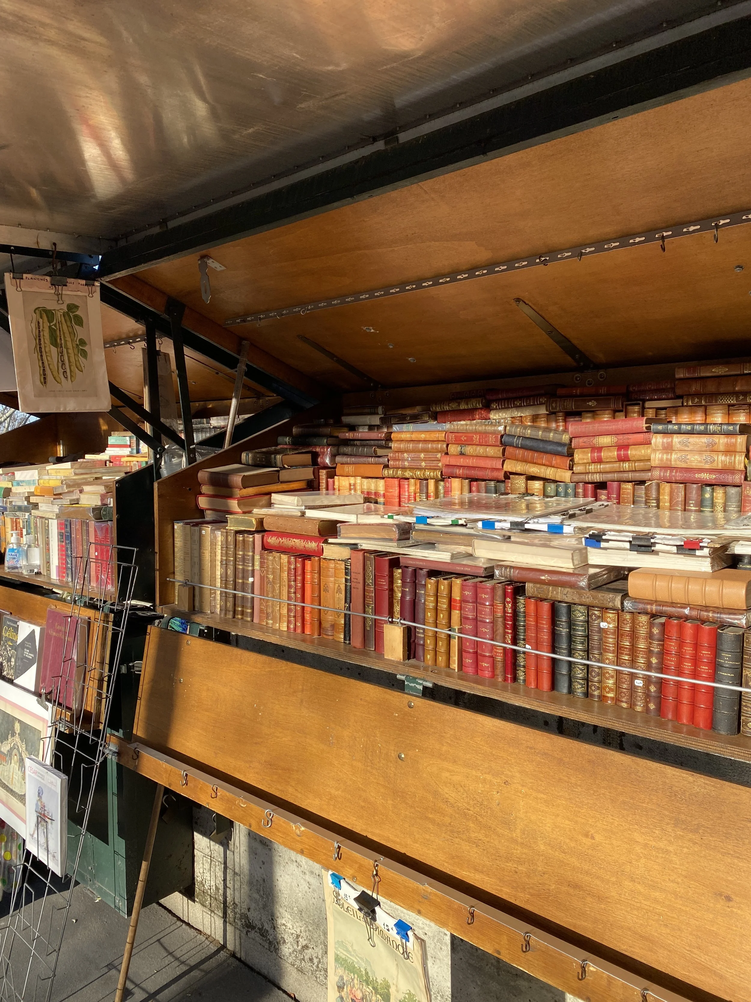 Bookshelves filled with old hardcover books arranged in a vintage bookstore or used book shop.