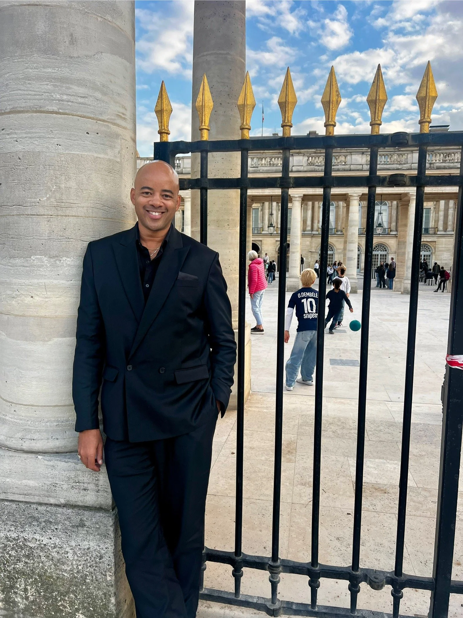 Ethan standing in Paris wearing a black suit.
