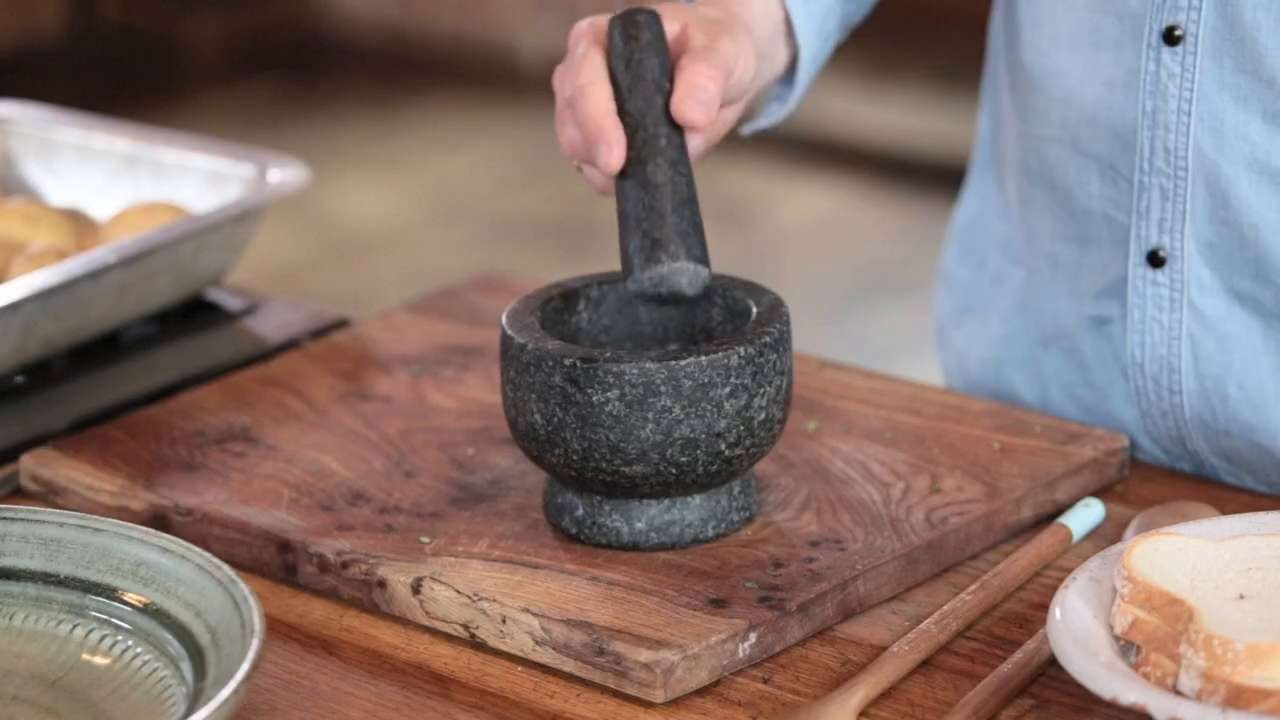 Jamie oliver useing a pestle and mortar.