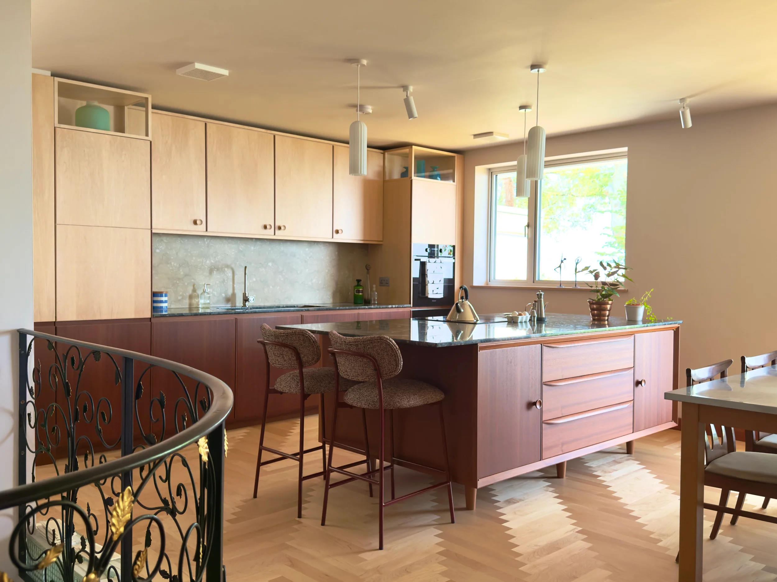 Inspired by the home's mid-century character, this bespoke kitchen combines Sapele and Maple cabinetry to create warmth and balance. A furniture-inspired island with turned legs and custom detailing sits at its heart, while handcrafted features throu