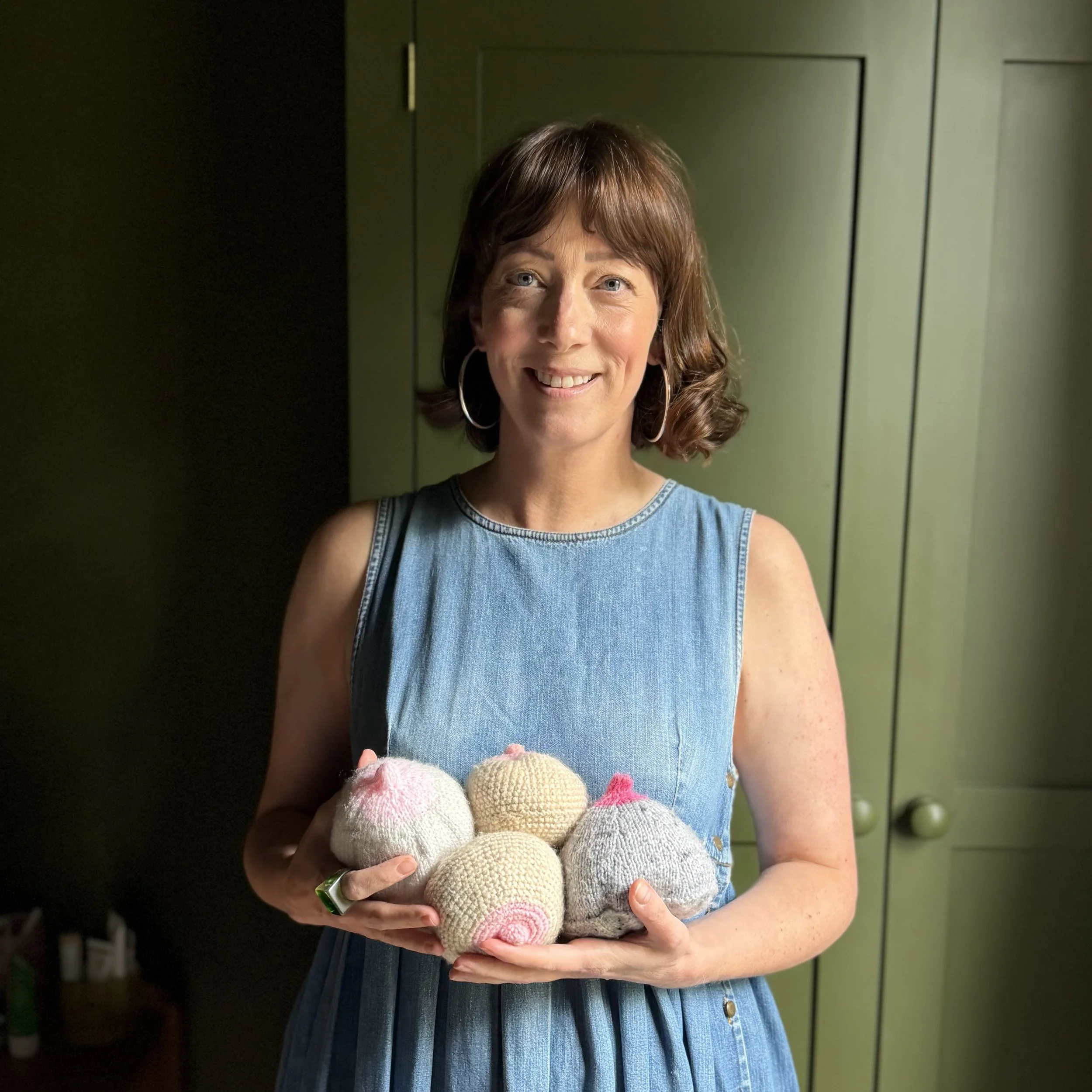 Claire Davis IBCLC holding a collection of different sized knitted breasts: used to aid breastfeeding demonstrations