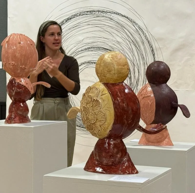 the artist is seen behind ceramic sculptures during the artist gallery talk