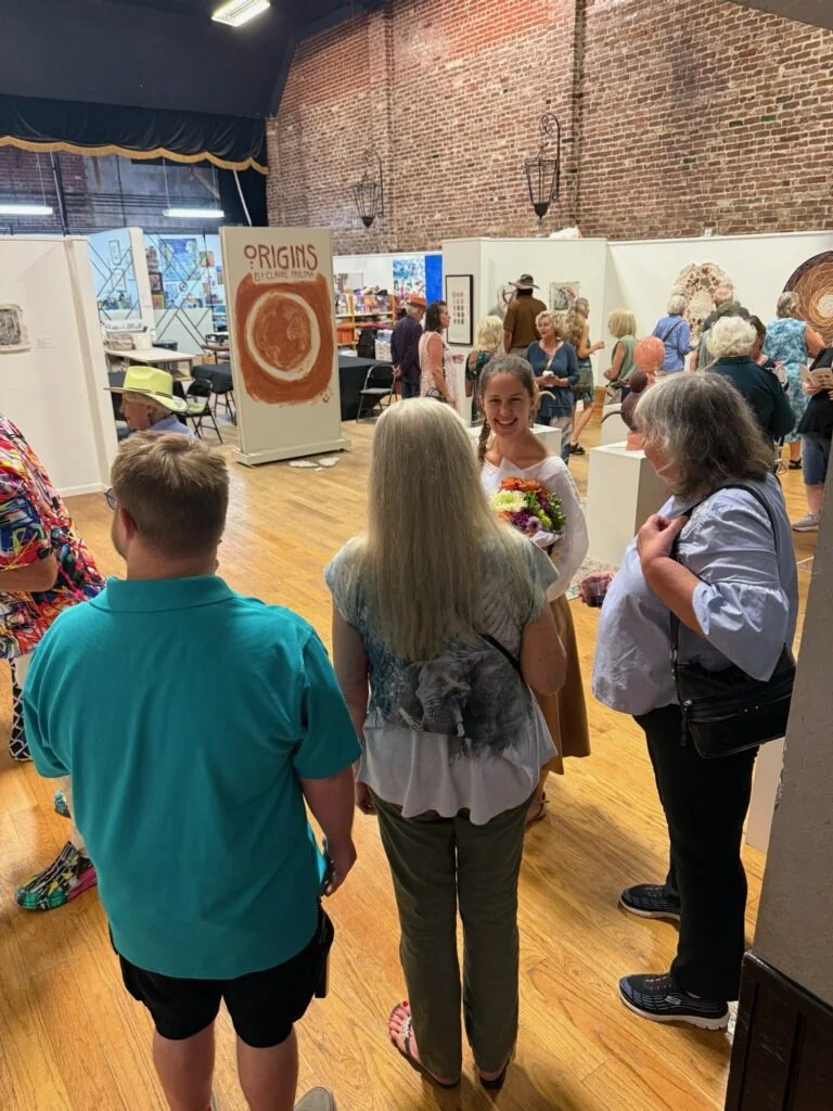 interior view of the gallery during the opening reception showing many visitors interacting with the artist and viewing the artwork