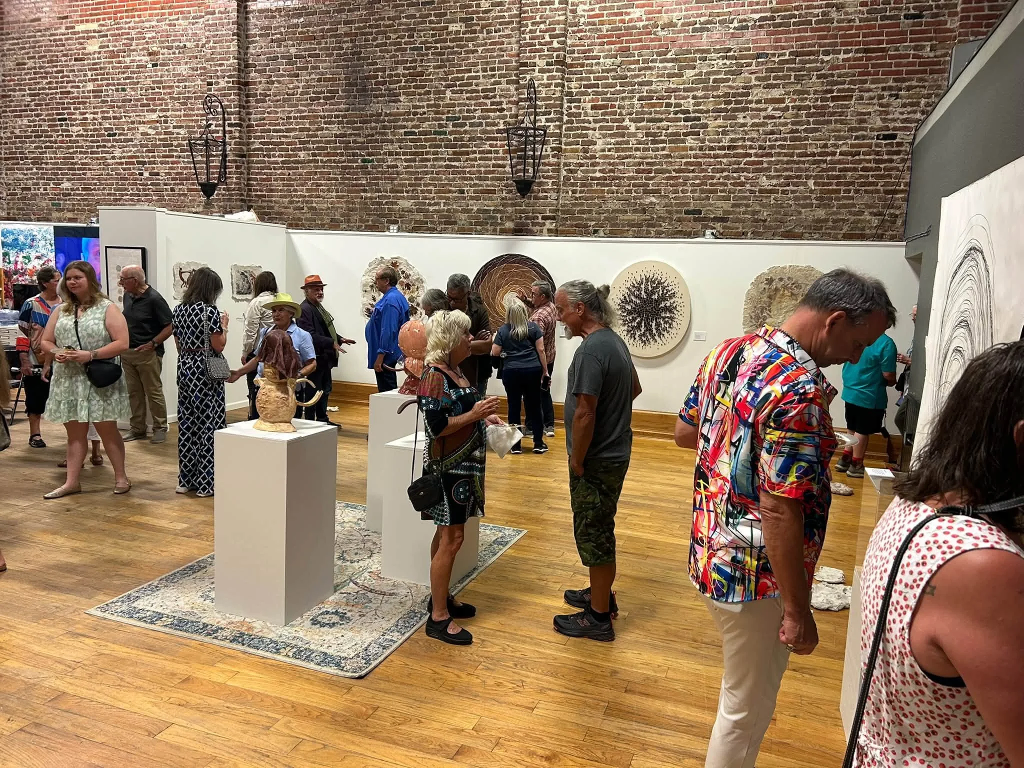 interior view of the gallery during the opening reception showing many visitors interacting with each other and viewing the artwork