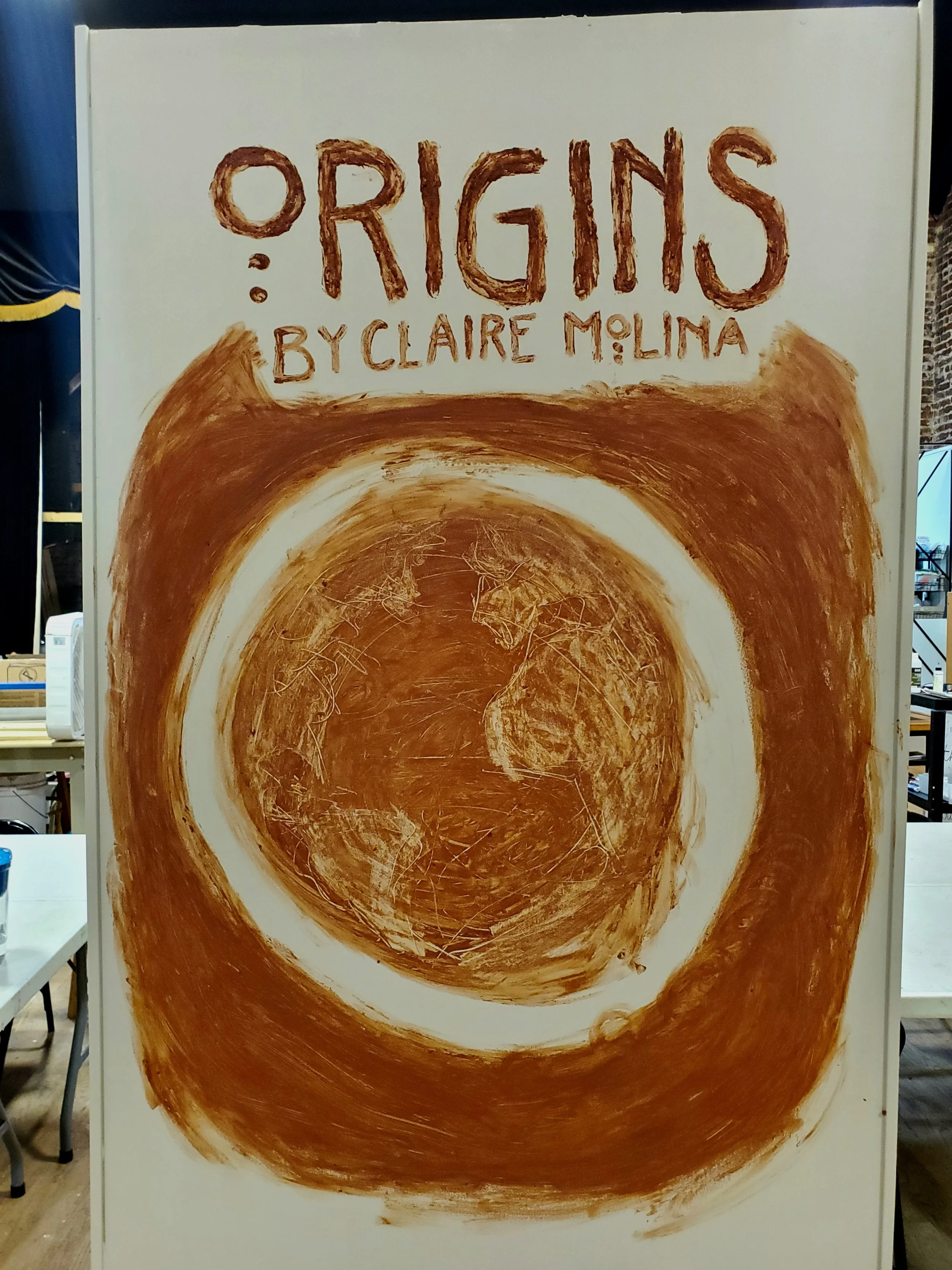 moving gallery wall featuring a hand painted design of the show title, Origins by Claire Molina, and a red circle with an earth design