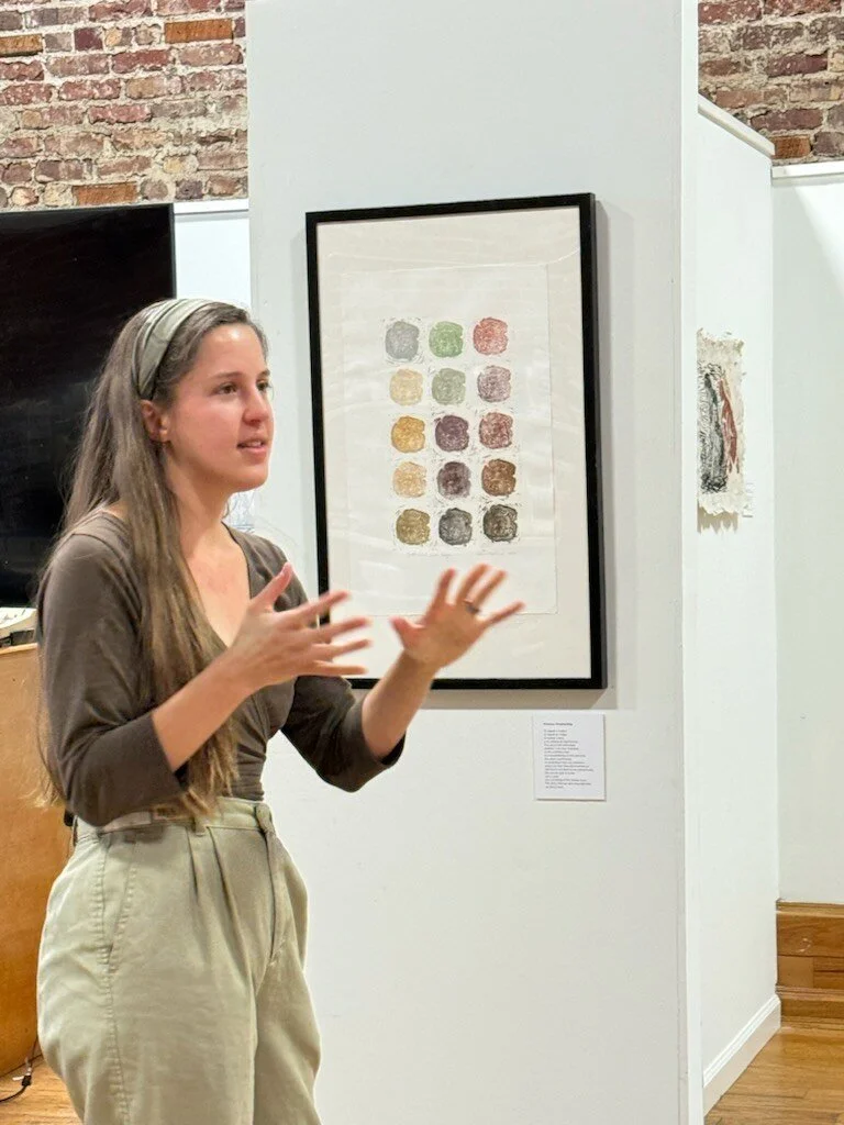 an interior view of the gallery showing the artist with expressive hands describing her artwork during the artist gallery talk