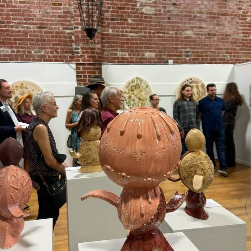 interior view of the gallery during the opening reception showing a large ceramic sculpture with visitors viewing artwork in the background