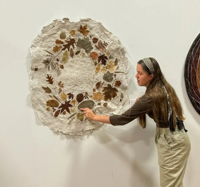 the artist demonstrated the flexibility of preserved leaves on an artwork during the artist gallery talk