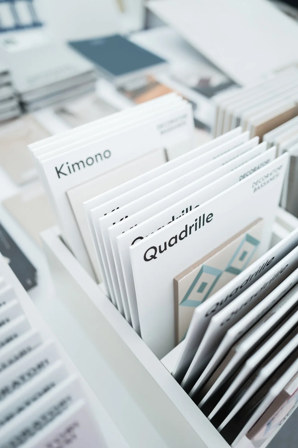 Close-up of design and architecture books on a white shelf, including titles like "Kimono" and "Quadrille."