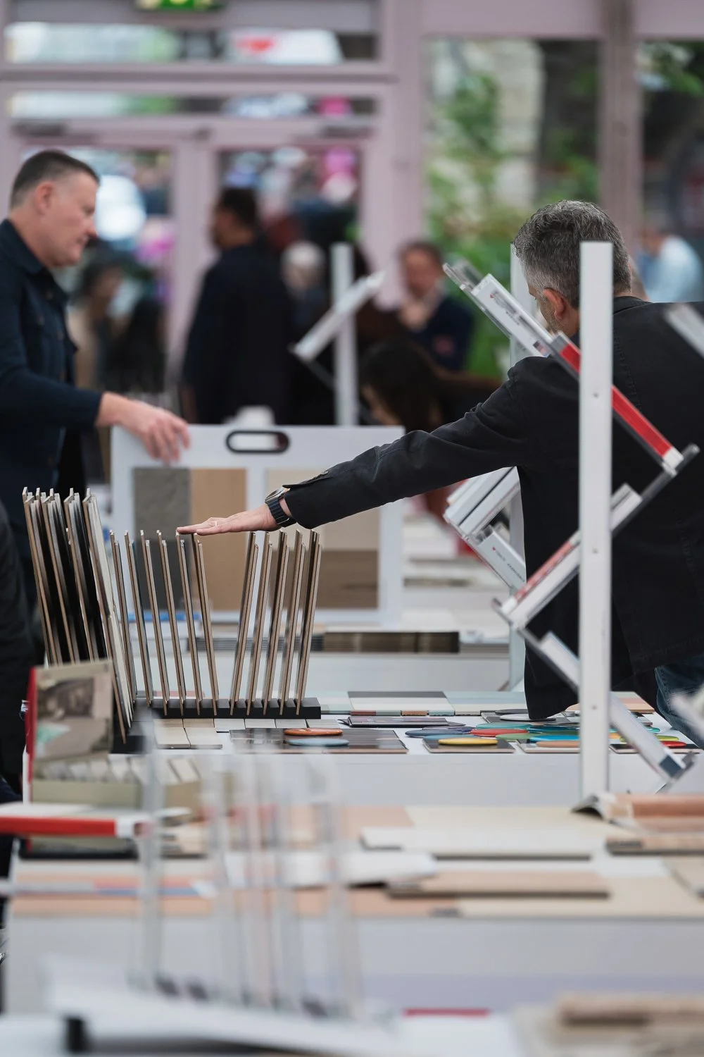 People browsing tile samples at a showroom display table.