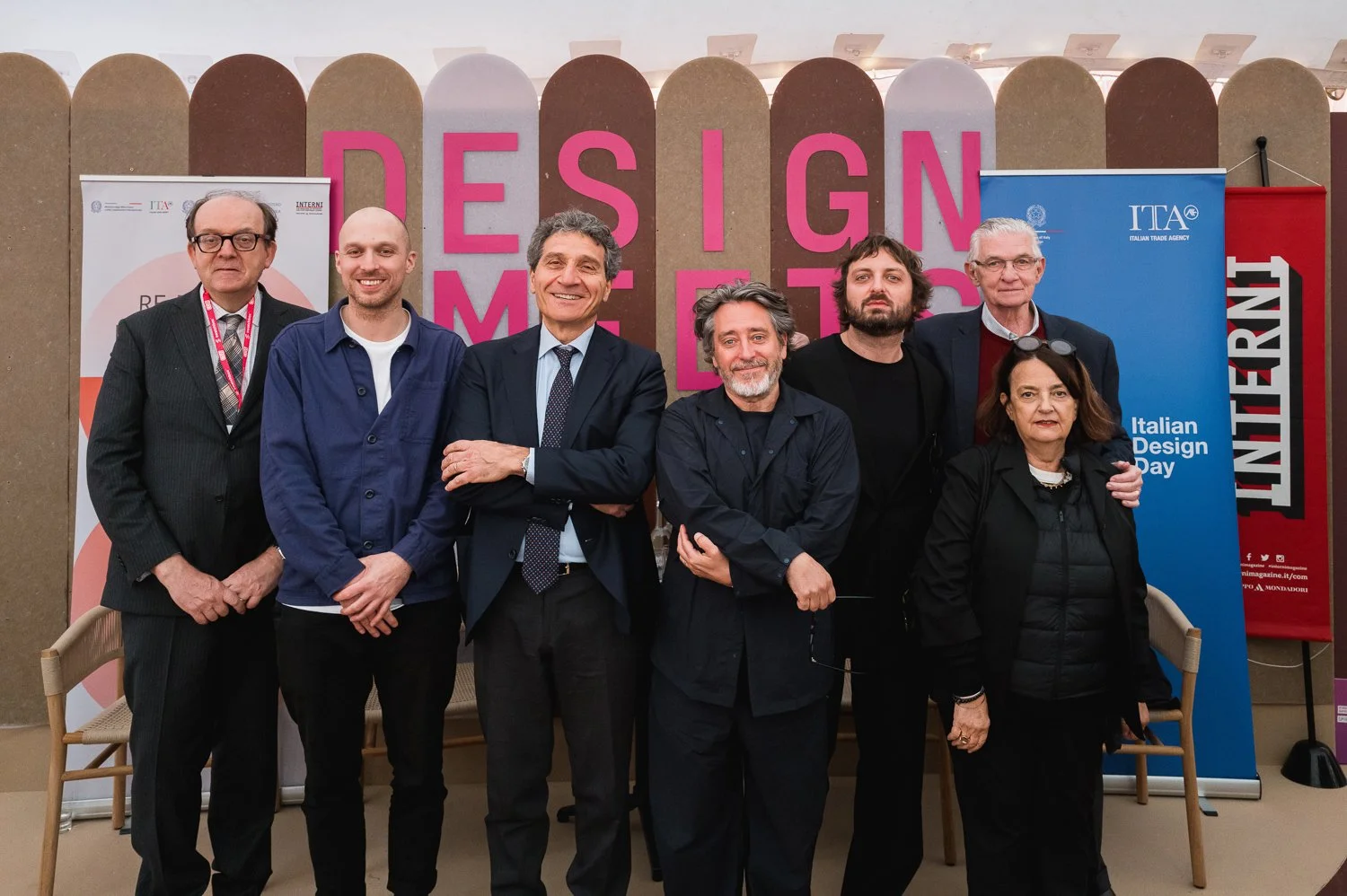 Group of seven people posing at Italian Design Day event with 'DESIGN' signage in the background.