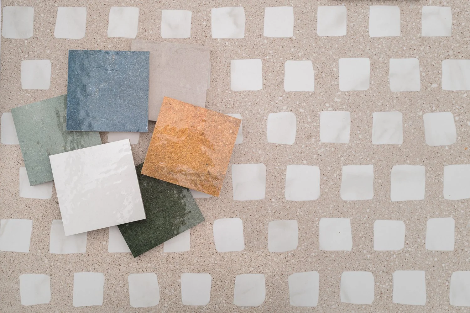 Various colored square tiles on a concrete surface with white square tiles arranged in a grid pattern.