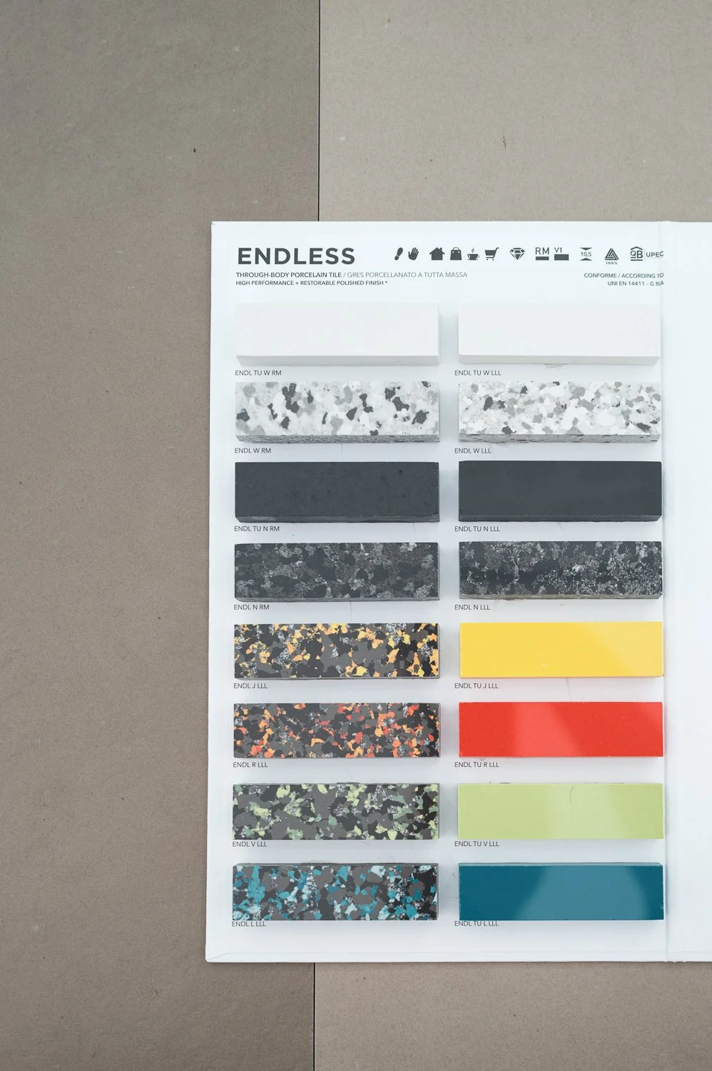 Sample display of terrazzo porcelain tiles in various colors and patterns on a white board.