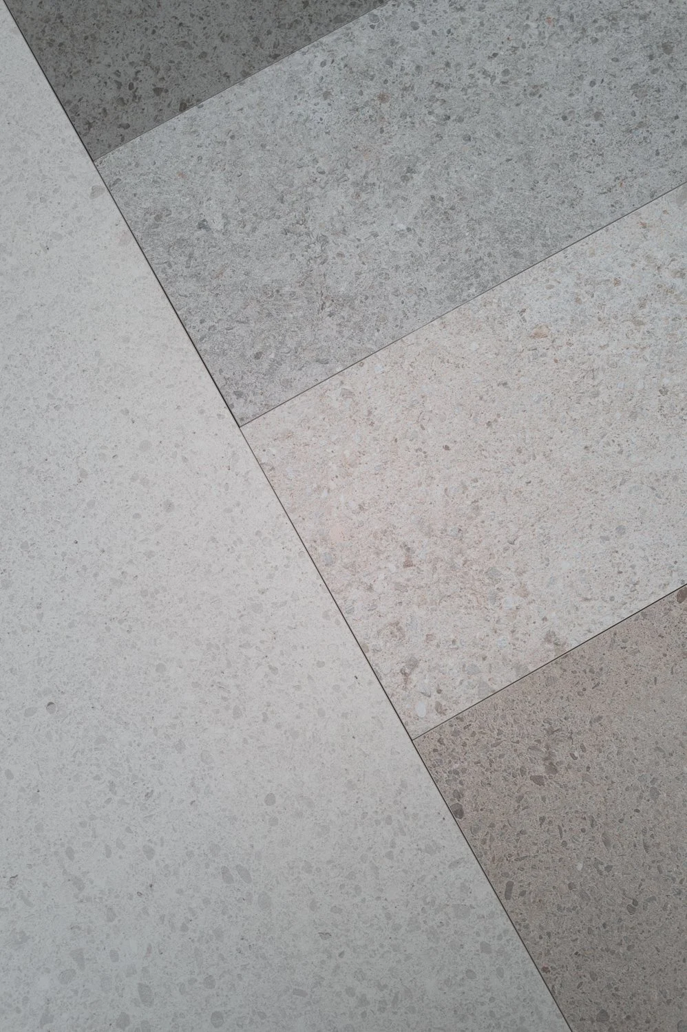 Close-up of different textured, colored tiles on a floor, arranged in a geometric pattern.