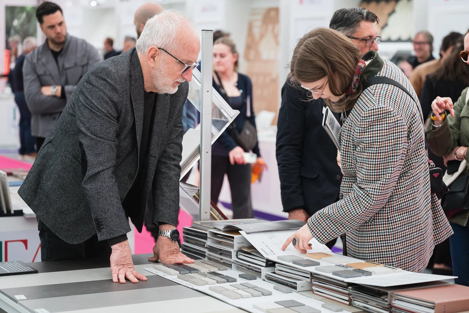 People examining fabric samples at a trade show or store.