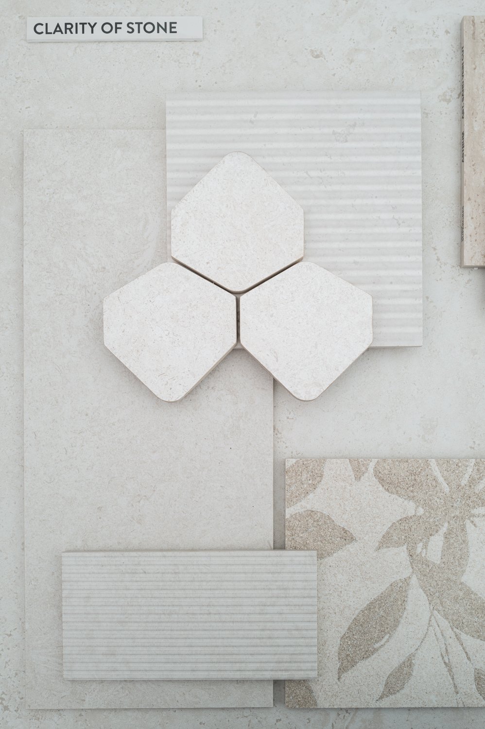 A collection of light-colored stone and tile samples, including hexagonal, rectangular, and patterned tiles, arranged for comparison or selection.
