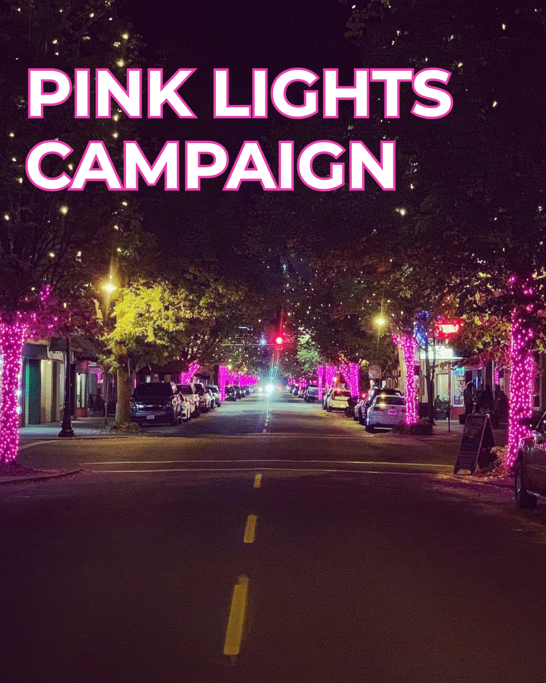 city street at night lined with trees covered in pink string lights